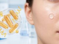 Imagem conceitual que conecta saúde intestinal e cuidados com a pele. À esquerda, uma esfera translúcida flutuante contém cápsulas douradas brilhantes de probióticos e formas espirais abstratas, contra um fundo clínico e de laboratório desfocado em tons de azul e branco. À direita, um close-up da lateral do rosto de uma mulher com pele impecável, iluminada e hidratada, destacando uma única gota redonda e transparente de sérum em sua bochecha.